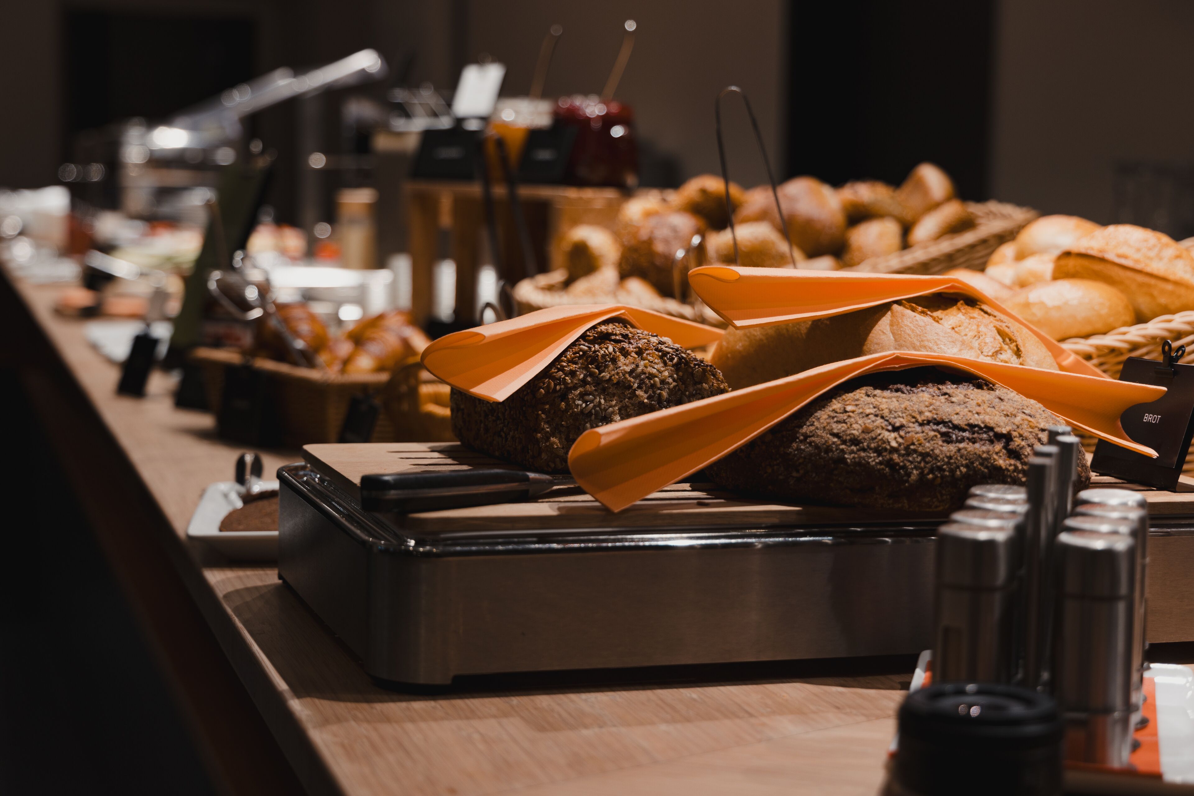 Un buffet proposant une variété de pains et de viennoiseries, un coin café, ainsi qu’un salero-poivrier.