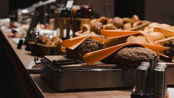 Un buffet proposant une variété de pains et de viennoiseries, un coin café, ainsi qu’un salero-poivrier.