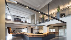 A spacious, multi-level interior with a central reception area, high ceilings, and a mezzanine level. - Factory Hotel (Münster)