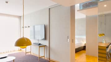 Una habitación de hotel moderna con cama, escritorio, televisor y zona de comedor.