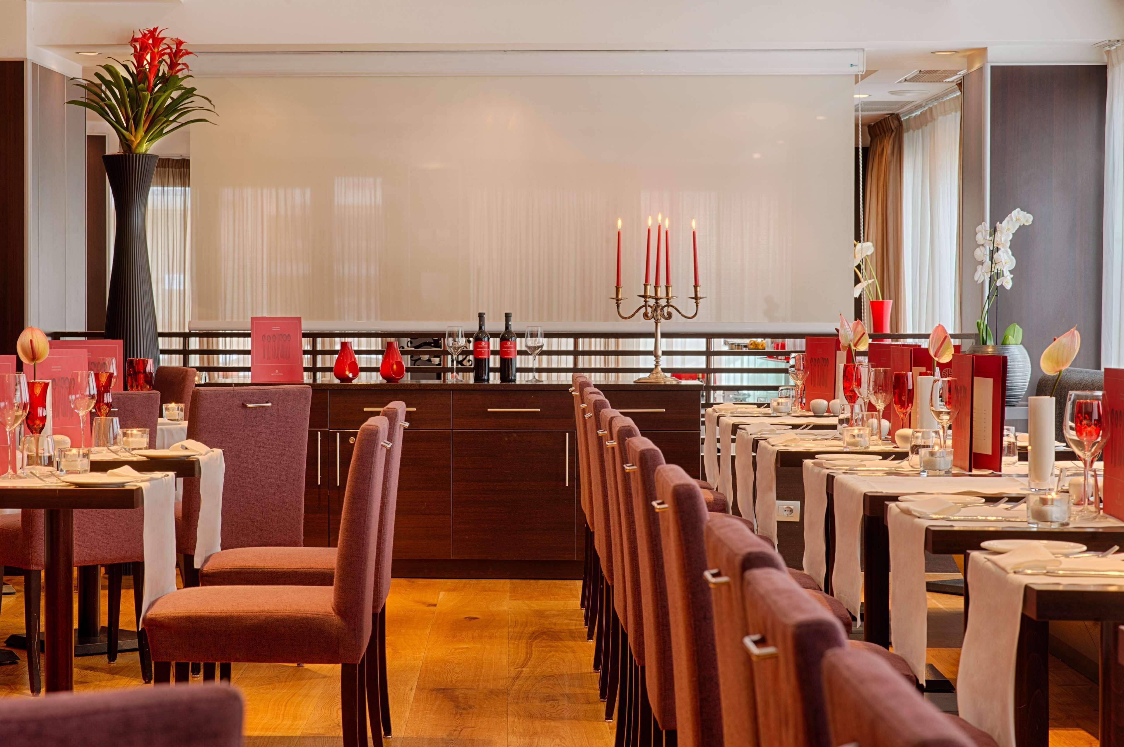 Un restaurant doté d’un long comptoir, de chaises rouges et d’un lustre décoratif central.