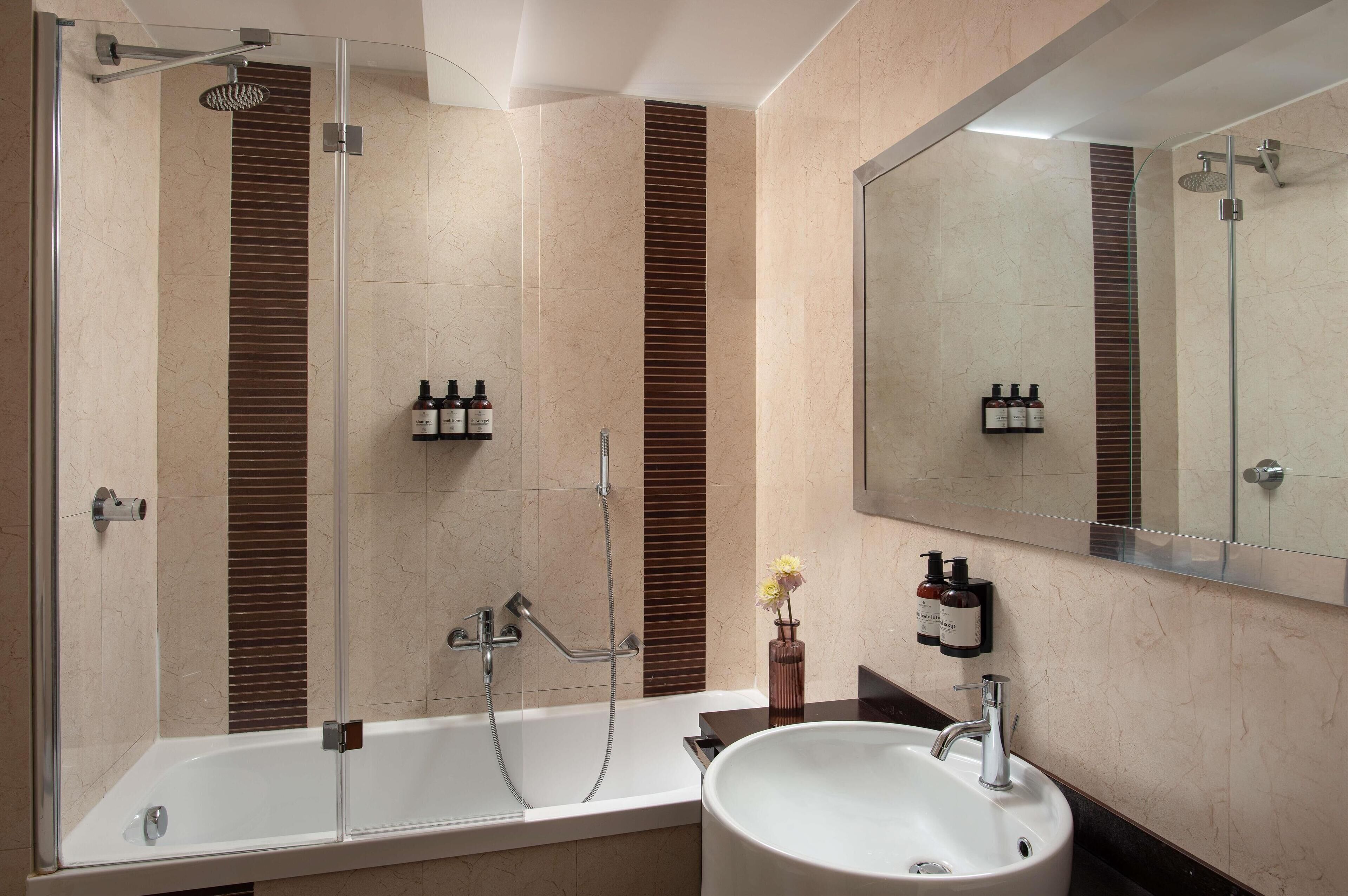 A modern bathroom with a glass-enclosed shower, a freestanding bathtub, and a sink with a mirror above.