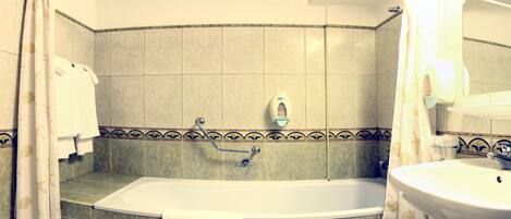 Un baño con bañera, lavamanos y secador de manos.