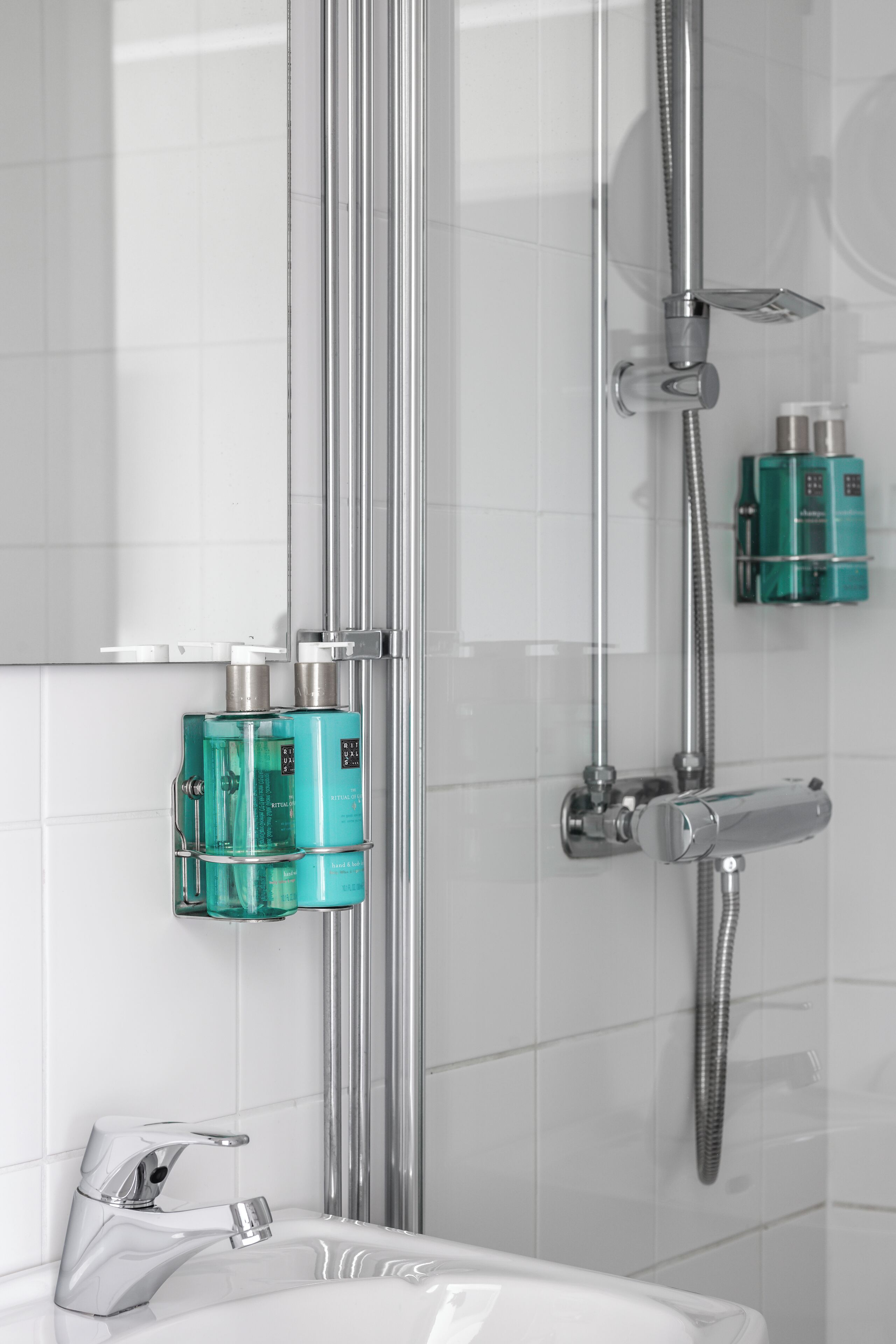 A modern bathroom with a glass-enclosed shower, chrome fixtures, and a white tiled wall.