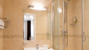 A bathroom with a toilet, sink, and glass-enclosed shower. - Parkwood at Marble Arch (London)