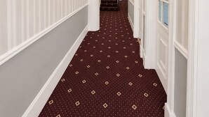 A hallway with a patterned carpet, a chandelier, and framed artwork on the walls. - Parkwood at Marble Arch (London)