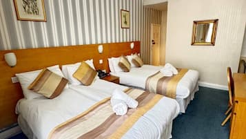 A hotel room with two beds, a wooden headboard, a desk, and a chair.