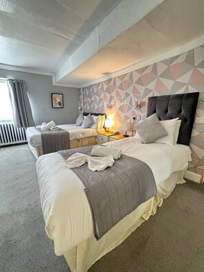A hotel room with two beds, a geometric-patterned wall, and a radiator. - Parkwood at Marble Arch (London)