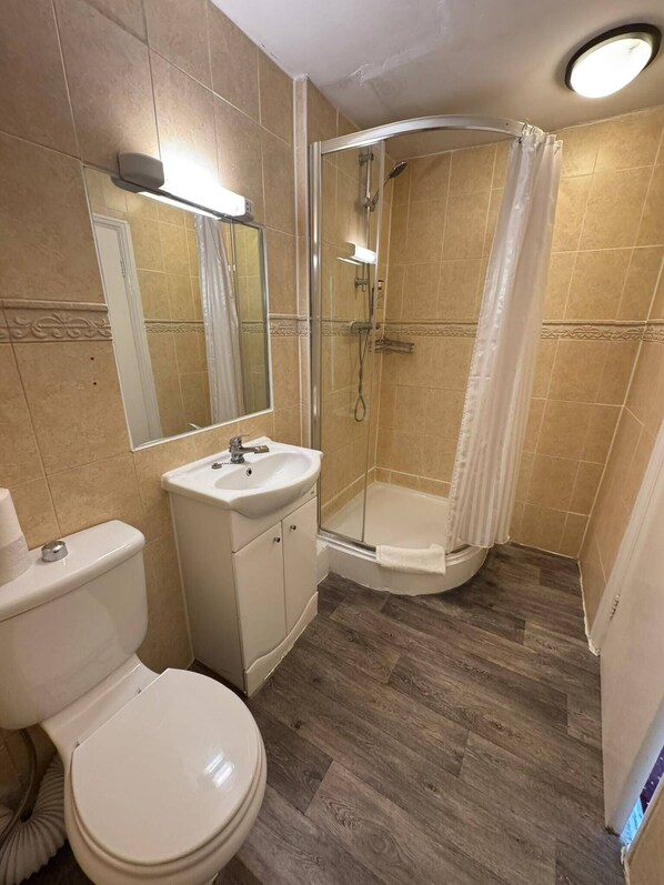 Un baño con inodoro, lavamanos y zona de ducha.