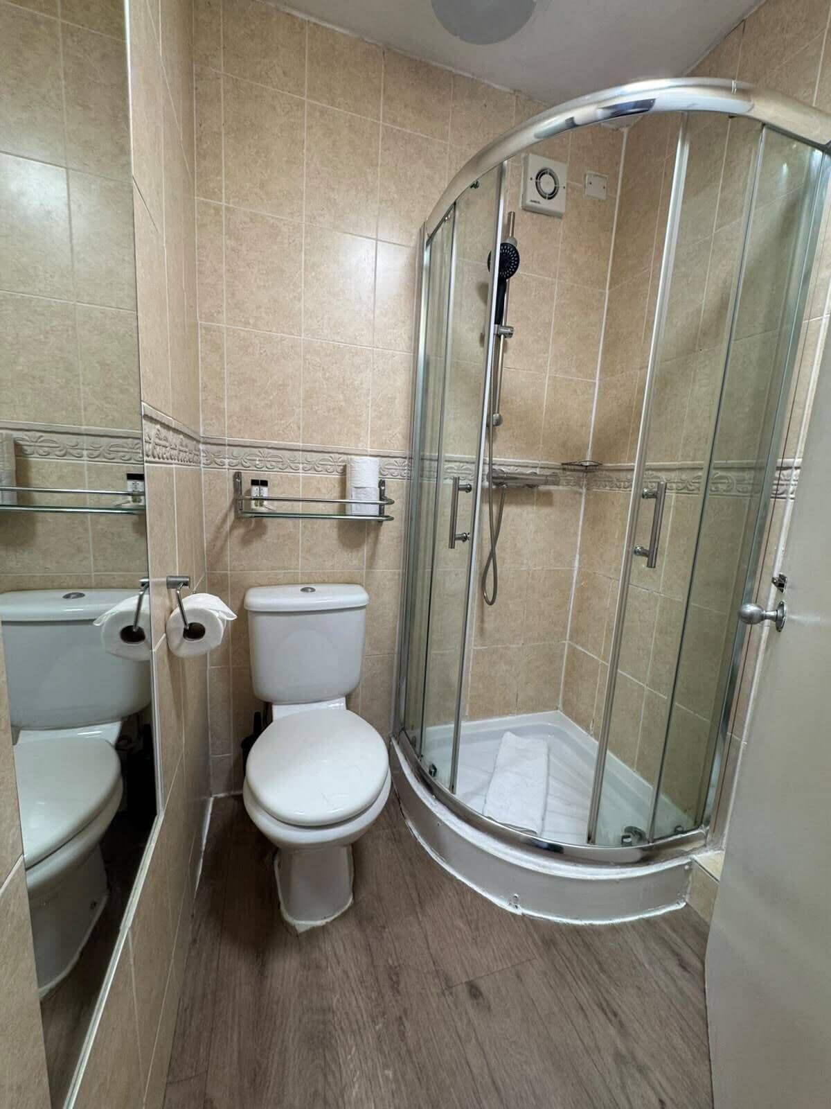 A bathroom with a toilet, a glass-enclosed shower, and a towel rack.