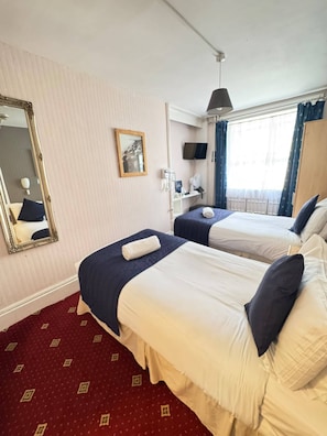 A hotel room with two beds, a large mirror, a television, and a window with curtains. - Parkwood at Marble Arch (London)