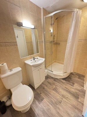 A bathroom with a toilet, sink, and glass-enclosed shower. - Parkwood at Marble Arch (London)
