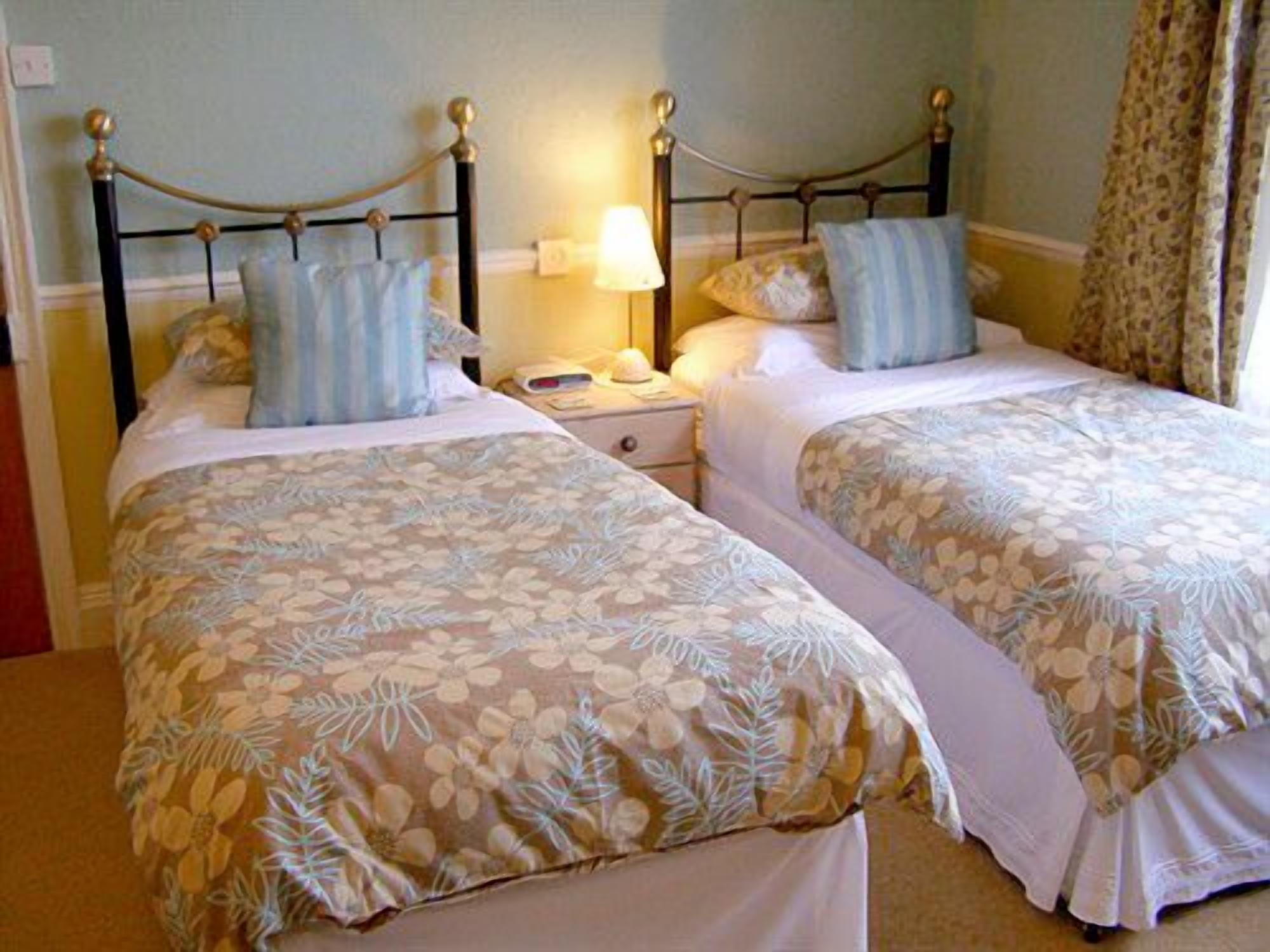 A double bed with floral bedding and a nightstand with a lamp.