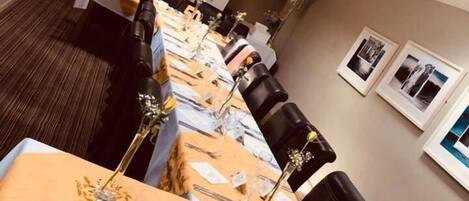 A long dining table with multiple chairs, set with fine china, glasses, and cutlery.