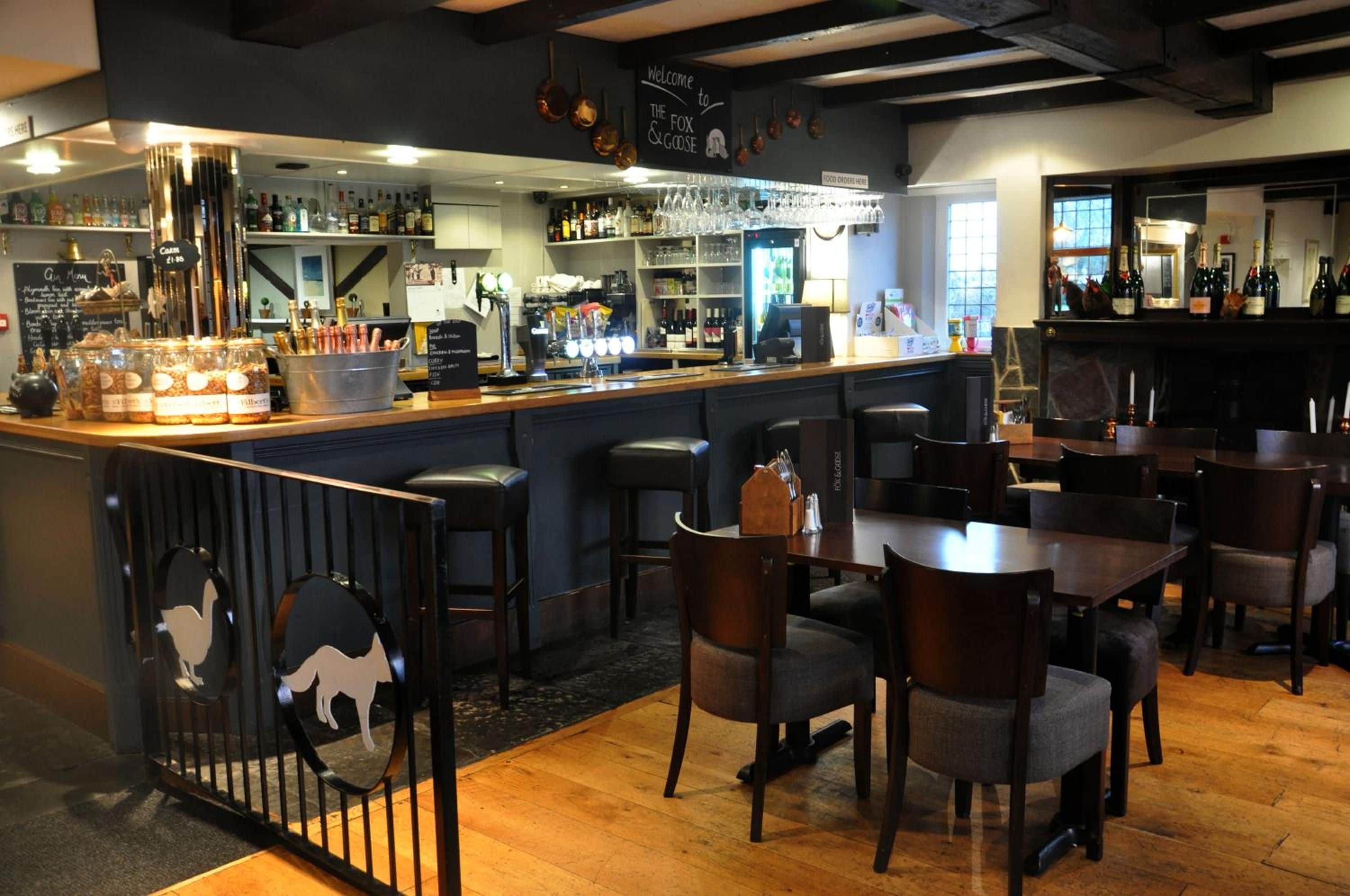 A bar area with a counter, stools, and a menu board.