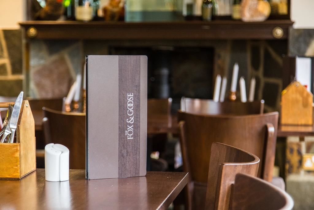 A neatly arranged table with a menu stand labeled "The Fox & Goose" in a restaurant setting.