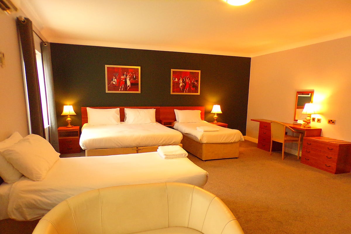 A hotel room with two beds, a desk, a chair, and two lamps.