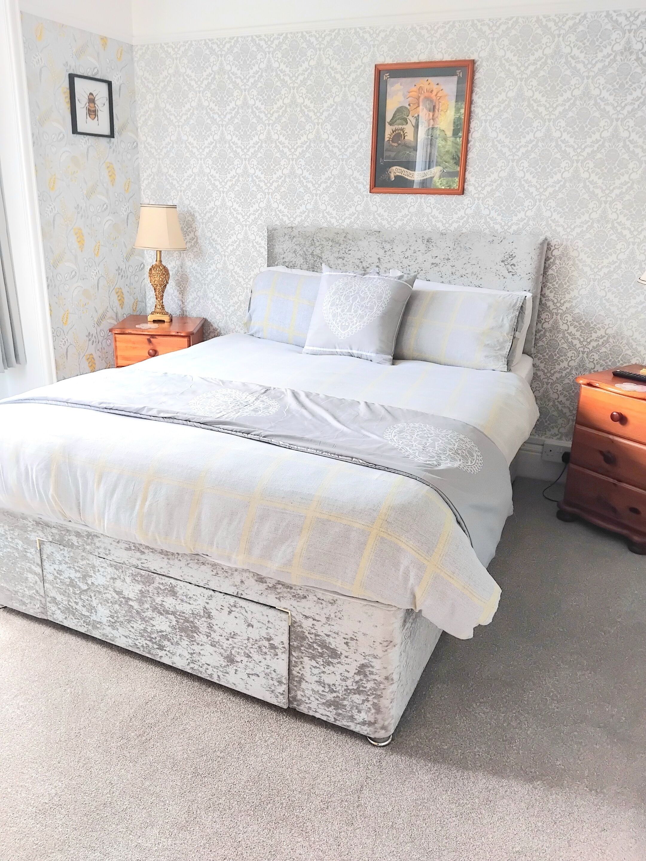 A bedroom with a bed, nightstands, a lamp, and a framed picture on the wall.