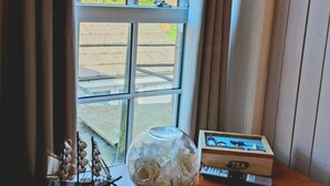 A wooden table with a vase of white flowers, a tea box, and a small ship model. - The Countryman Hotel (Camelford)