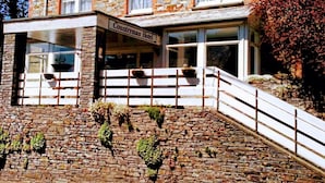 A stone building with a sign reading "Countryman Hotel." It features a stone facade, multiple windows, and a staircase leading to the entrance. - The Countryman Hotel (Camelford)