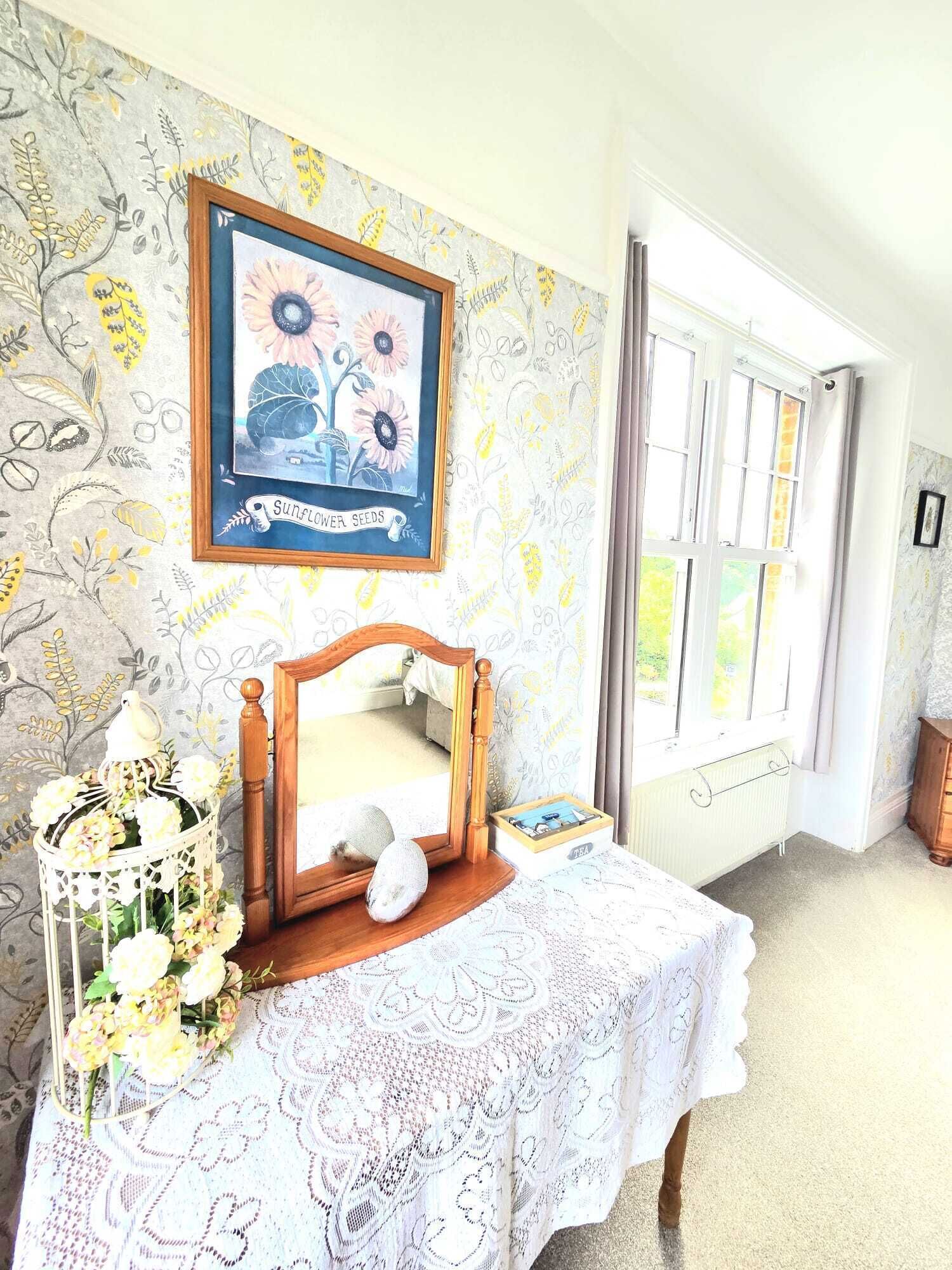 Una habitación con cama, una obra de arte enmarcada, un espejo y una ventana.