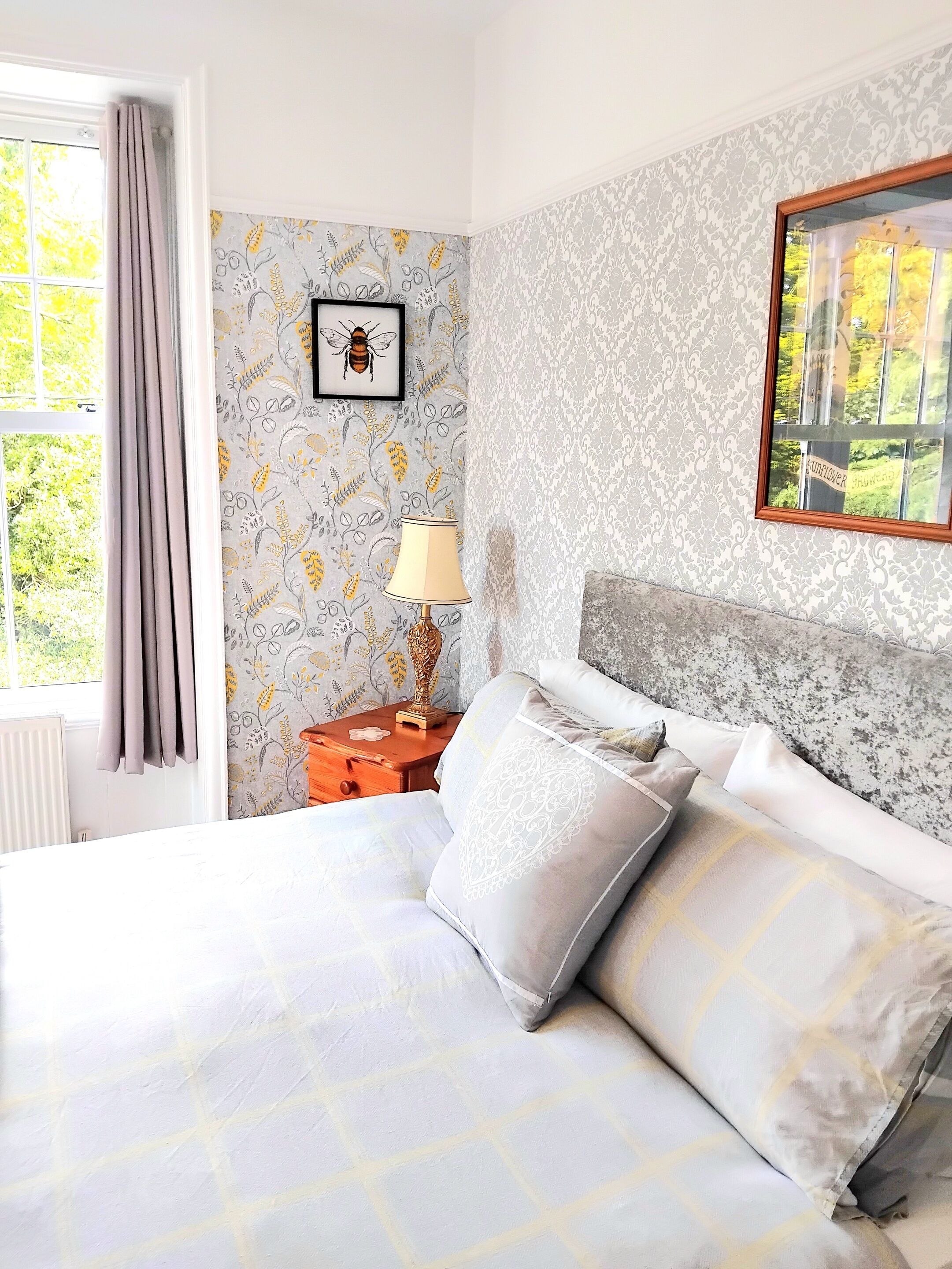 A neatly made bed with pillows, a bedside table with a lamp, and a framed picture on the wall.