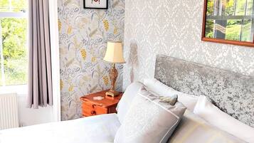 A neatly made bed with pillows, a bedside table with a lamp, and a framed picture on the wall.