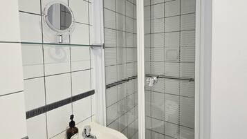 Une salle de bain avec un lavabo blanc, un miroir et une douche en verre.