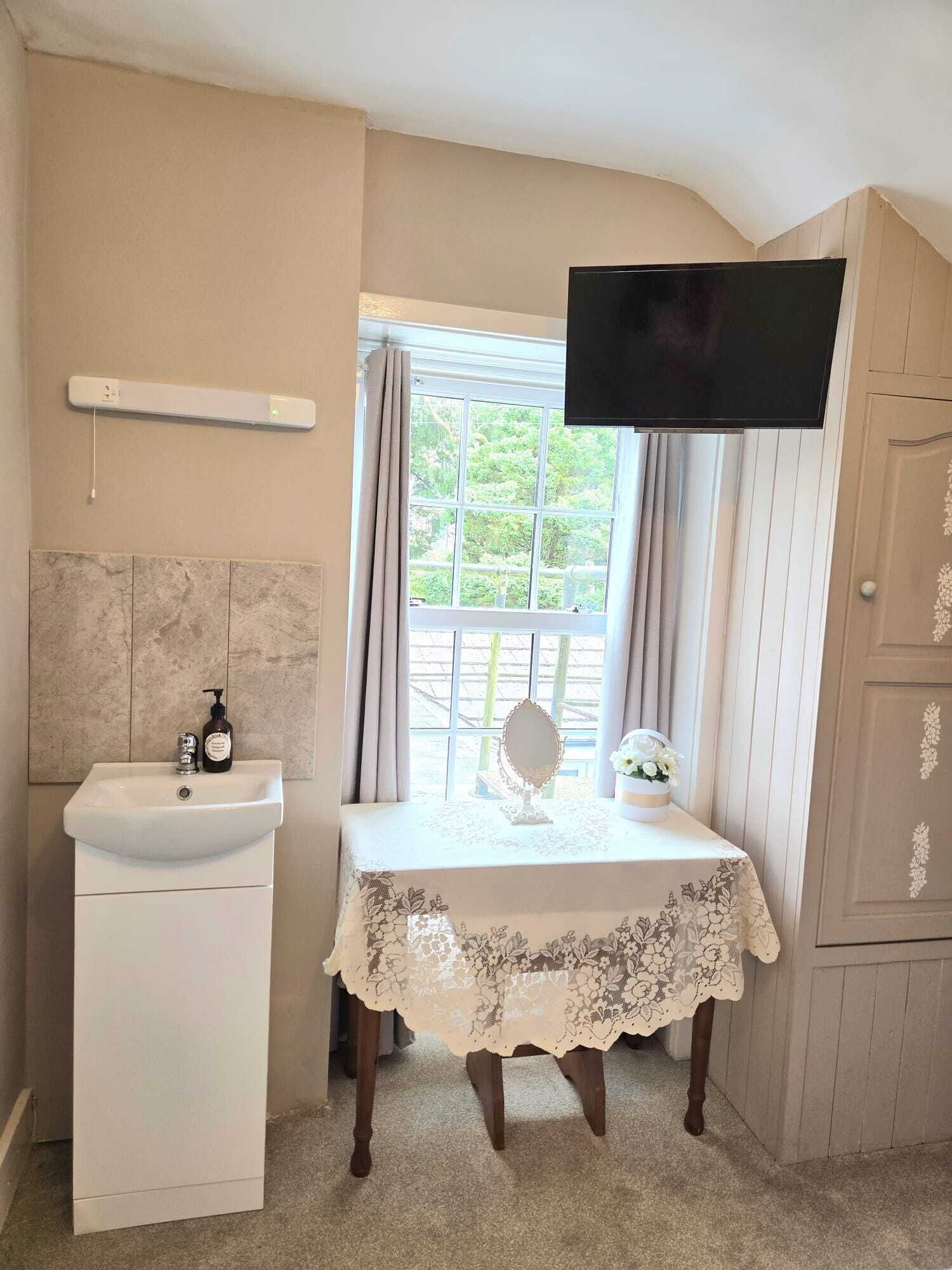 A bathroom with a sink, mirror, and table with a lace tablecloth.