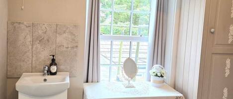 A bathroom with a sink, mirror, and table with a lace tablecloth.