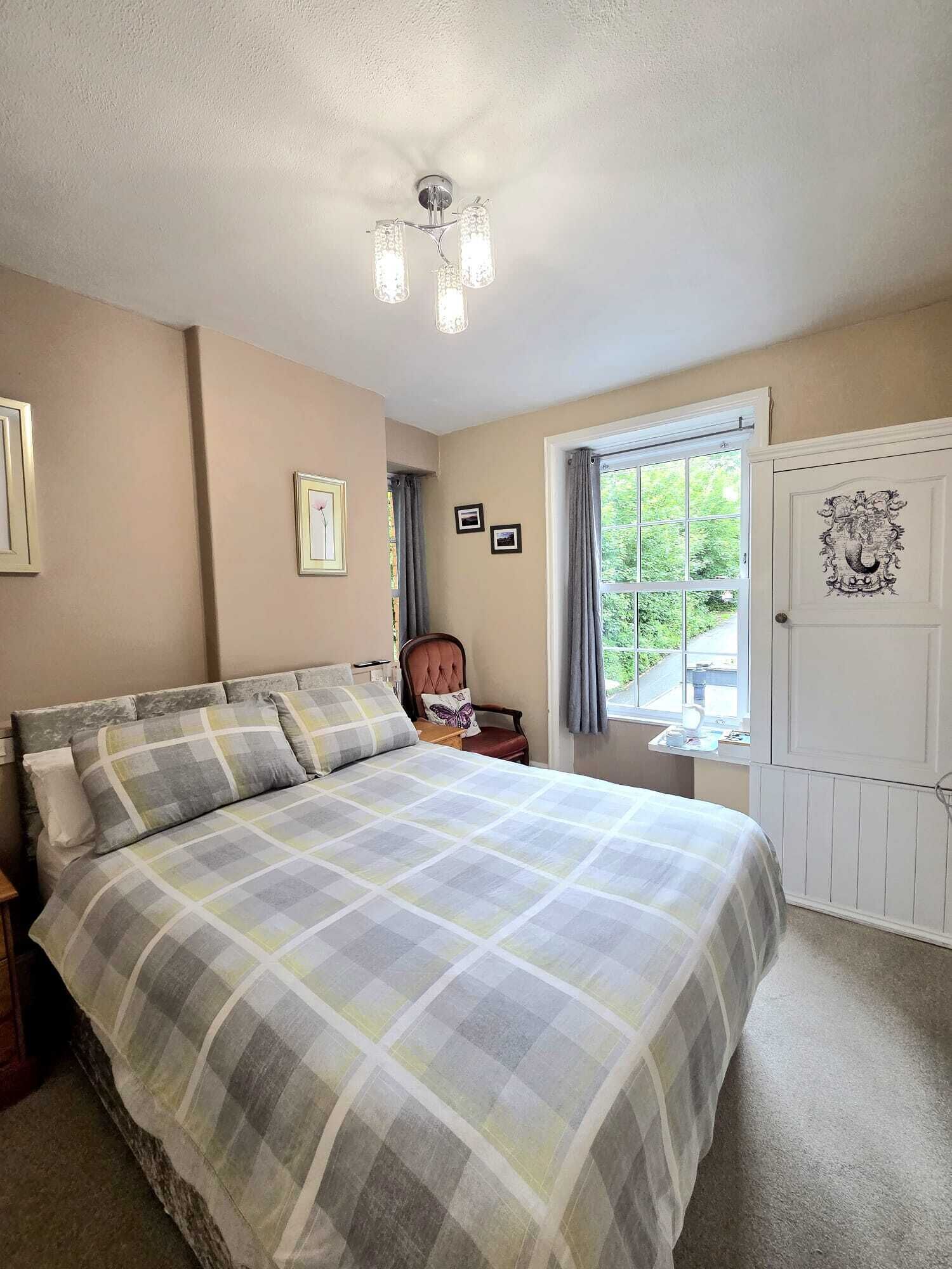 Een slaapkamer met een bed, een stoel, een raam en een deur.