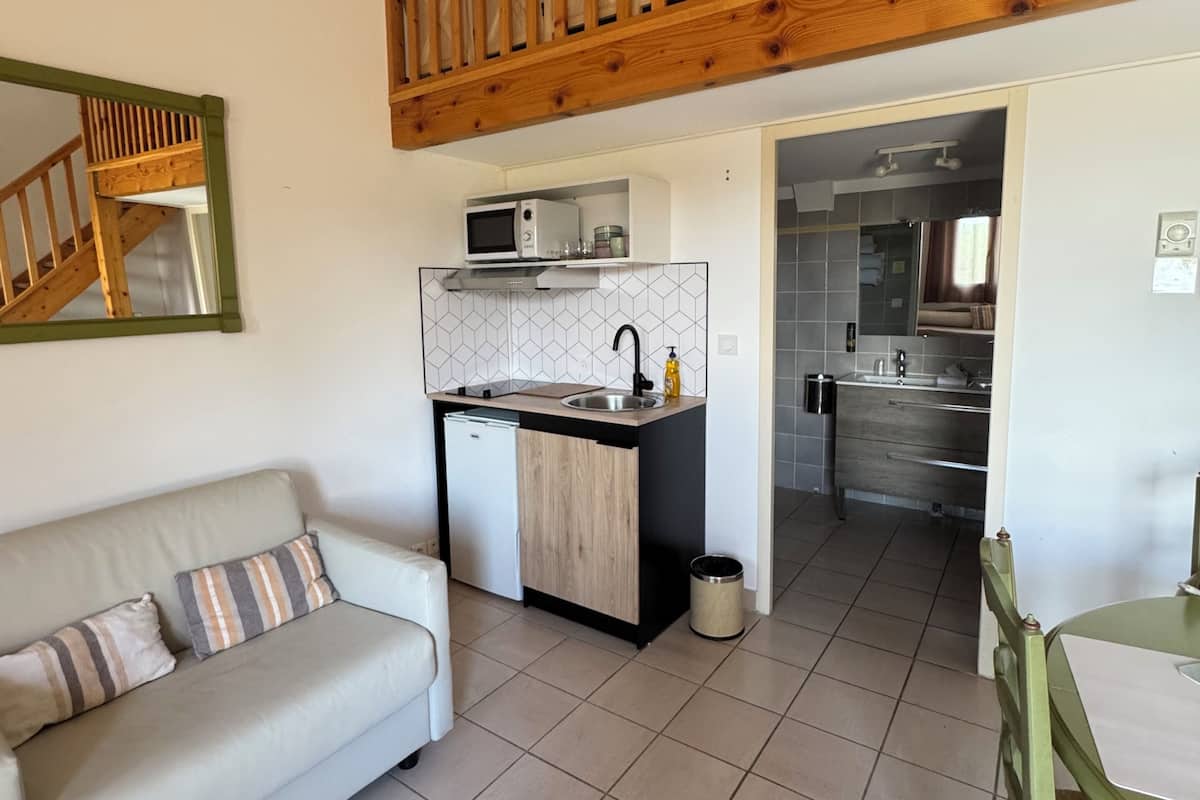A modern kitchen with a microwave, sink, and wooden upper floor railing.