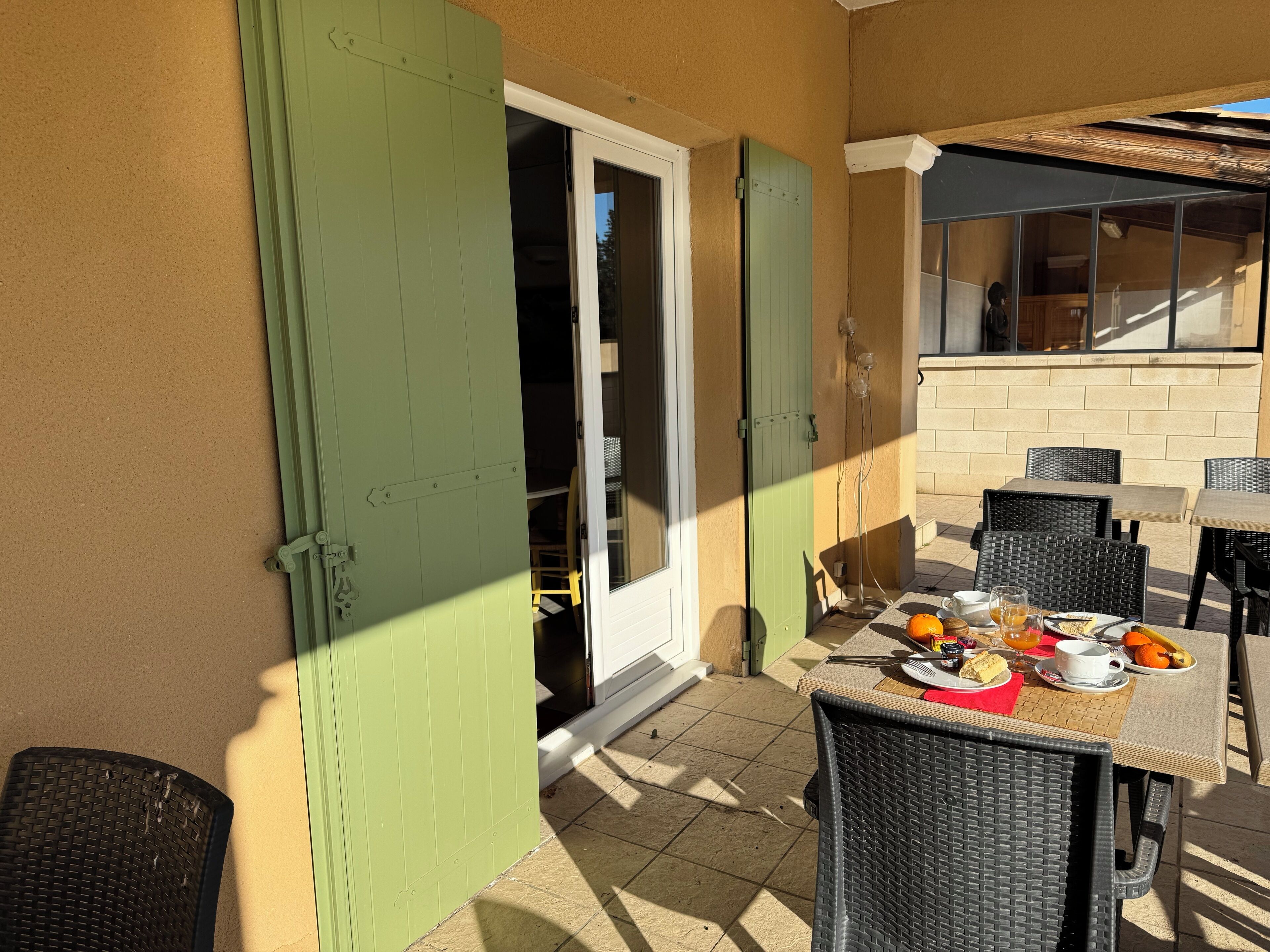 Un patio al aire libre con una mesa dispuesta para el desayuno, que incluye rodajas de naranja, un pastel y una taza.