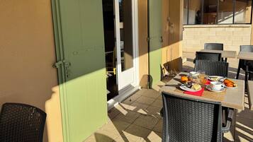 Un patio al aire libre con una mesa dispuesta para el desayuno, que incluye rodajas de naranja, un pastel y una taza.