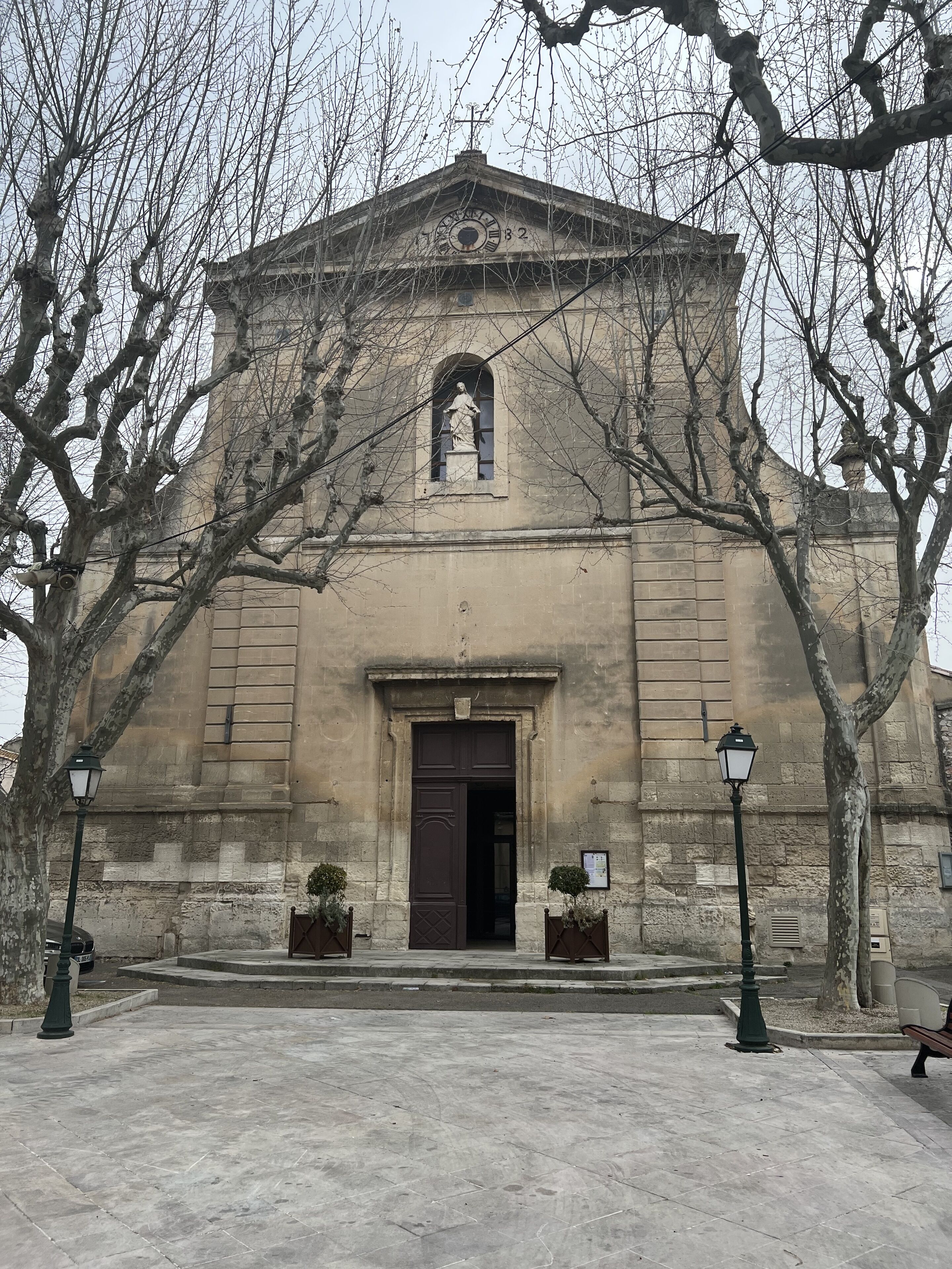 Un edificio histórico con un gran arco de entrada, un reloj y una estatua sobre la puerta.