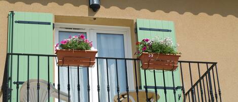 A balcony with two flower boxes, a white chair, and a small table.