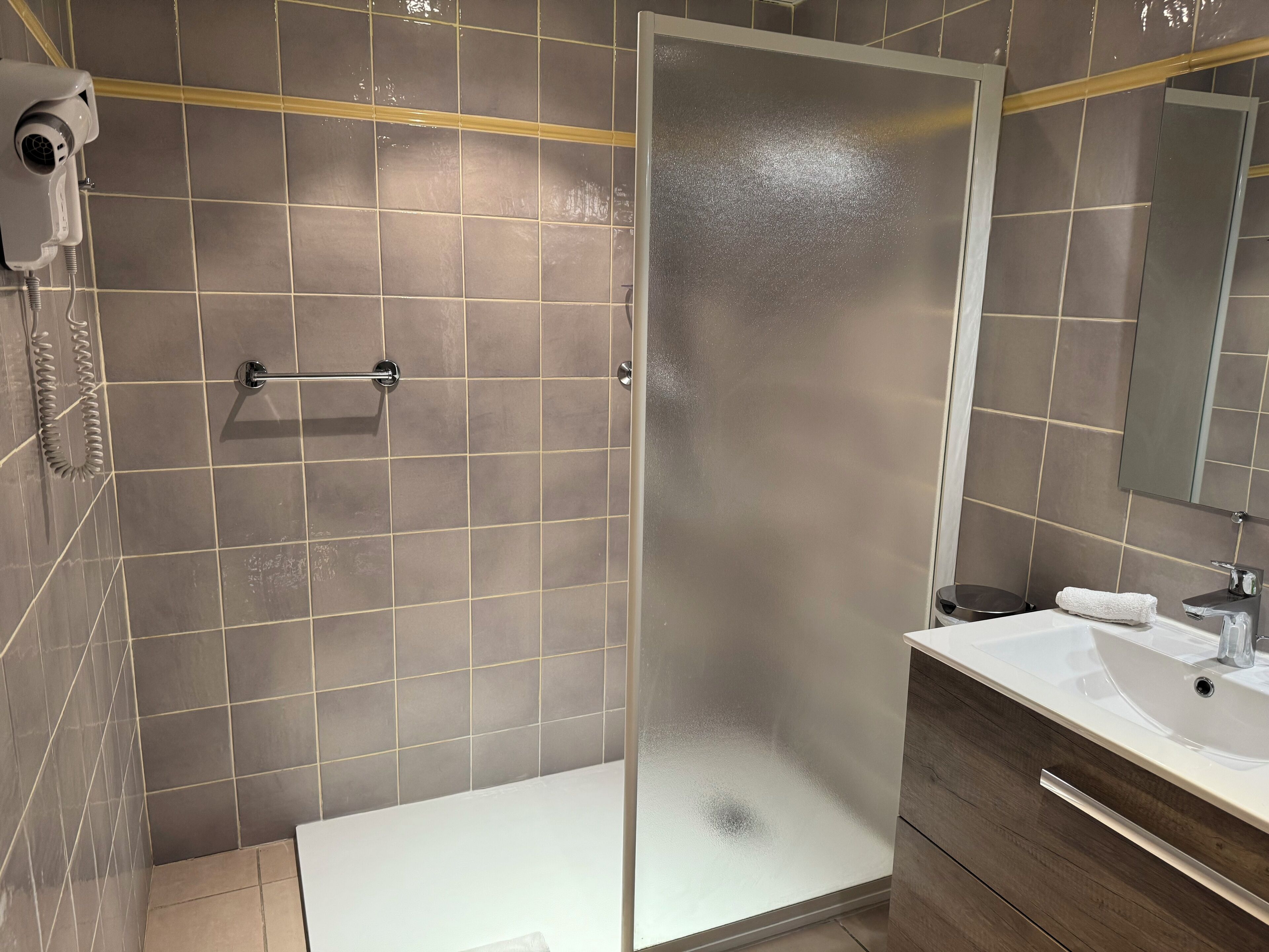 A modern bathroom with a glass shower enclosure, a white sink, and a mirror above the sink.