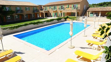 Una piscina al aire libre de temporada, sombrillas, tumbonas