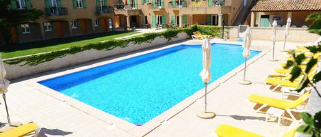 Piscina a l'aire lliure de temporada, para-sols i gandules