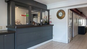 Un comptoir d’accueil avec une horloge, un panneau indiquant « animaux interdits » et un panneau indiquant « Central Phoenix Hotel ».