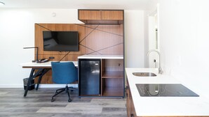 Une cuisine compacte dotée d’un téléviseur encastré, d’un petit réfrigérateur, d’un évier et d’un plan de travail moderne.
