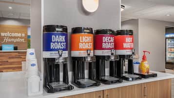 Una estación de café con cuatro dispensadores etiquetados como: tostado oscuro, tostado claro, descafeinado y agua caliente.
