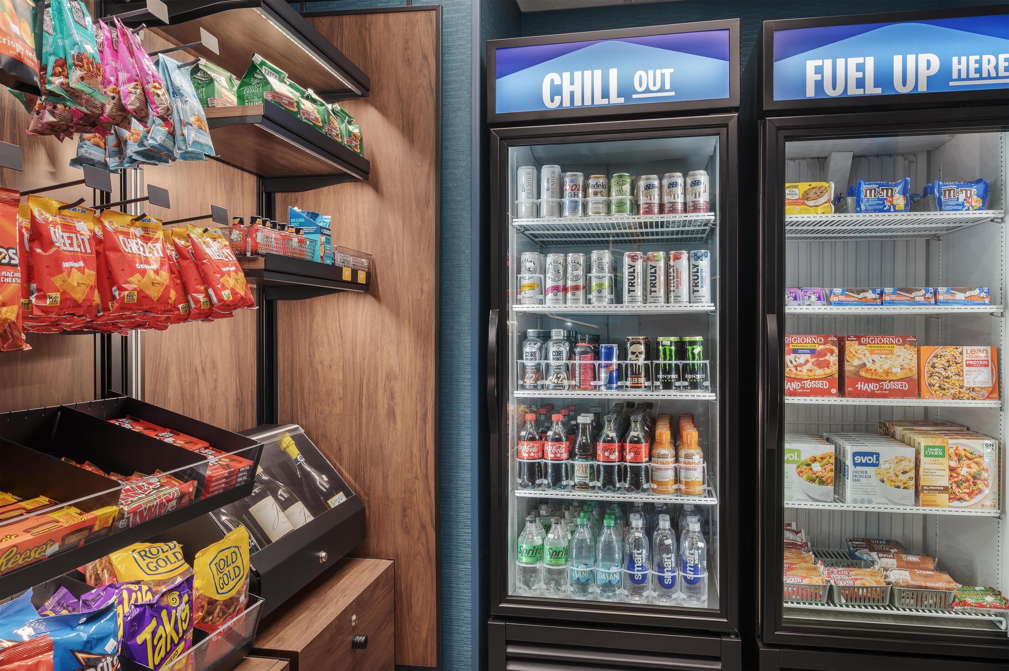 A snack and beverage vending area with 'CHILL OUT' and 'FUEL UP HERE' signs, various snacks, and beverages.