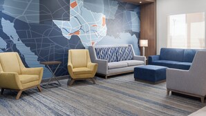 A lobby with a large map mural, two armchairs, a sofa, and a side table.