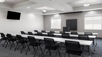 A conference room with a long table, chairs, a flat-screen TV, windows, and a projector.