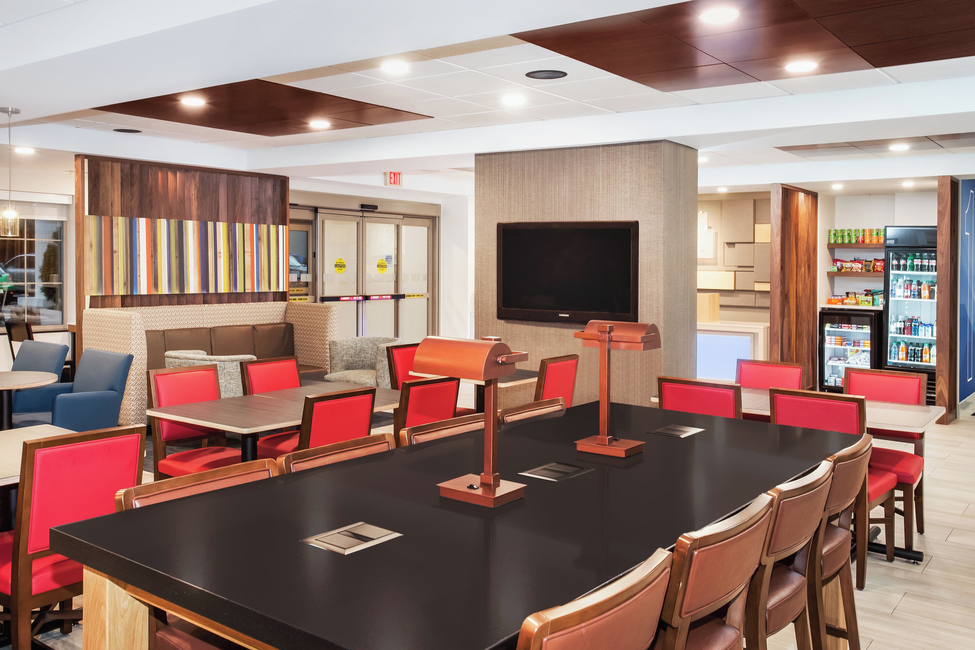 Un restaurante moderno con un amplio salón comedor, sillas rojas y un televisor de pantalla plana.