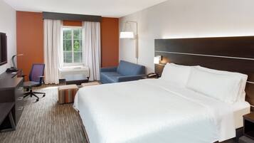Habitación de hotel con una cama grande, un escritorio con computadora, una silla y un ventanal con cortinas.