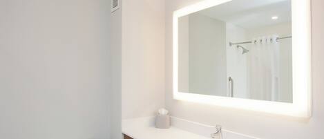 Un baño con inodoro, lavamanos y espejo con luz.