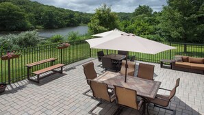 An outdoor patio with a table and chairs, a bench, and a large umbrella. - Holiday Inn Express Haskell - Wayne Area by IHG (Wanaque)