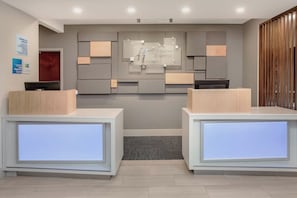 A reception area with two reception desks, a wall-mounted sign, and a wooden partition. - Holiday Inn Express Haskell - Wayne Area by IHG (Wanaque)